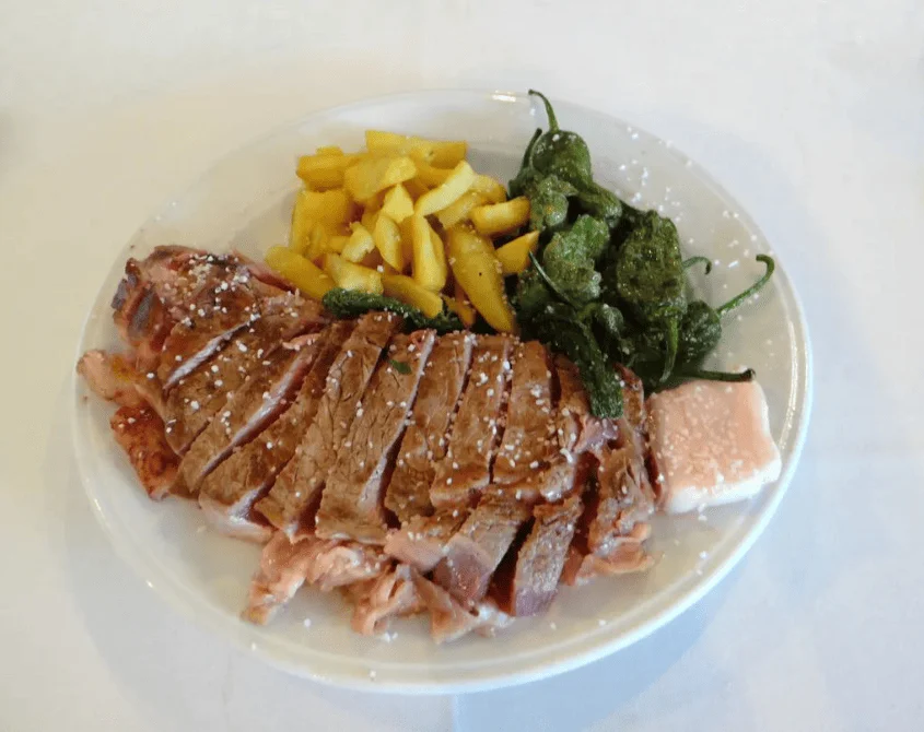 Plato con chuletón laminado, patatas fritas y pimientos